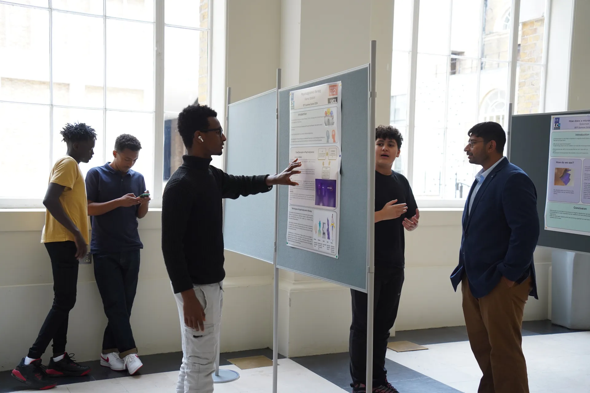 A student presenting their research poster on the final day
